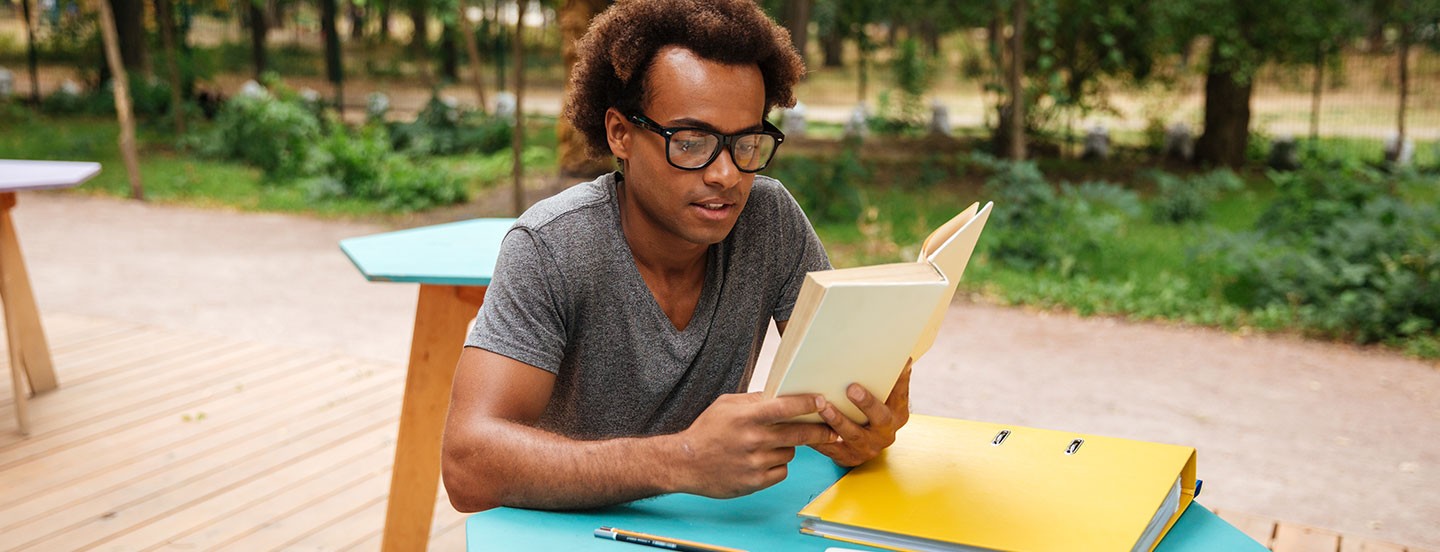 young man sitting and reading book outdoor