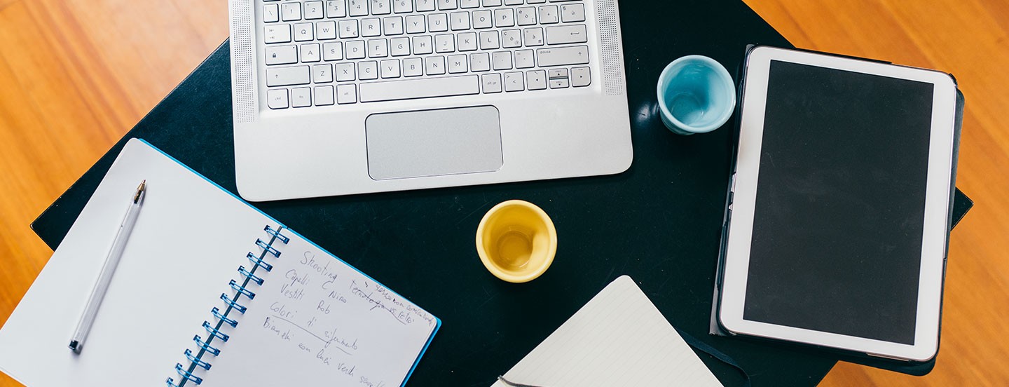 top view of office desk table with organizer notebook tablet pencil and cups of coffee