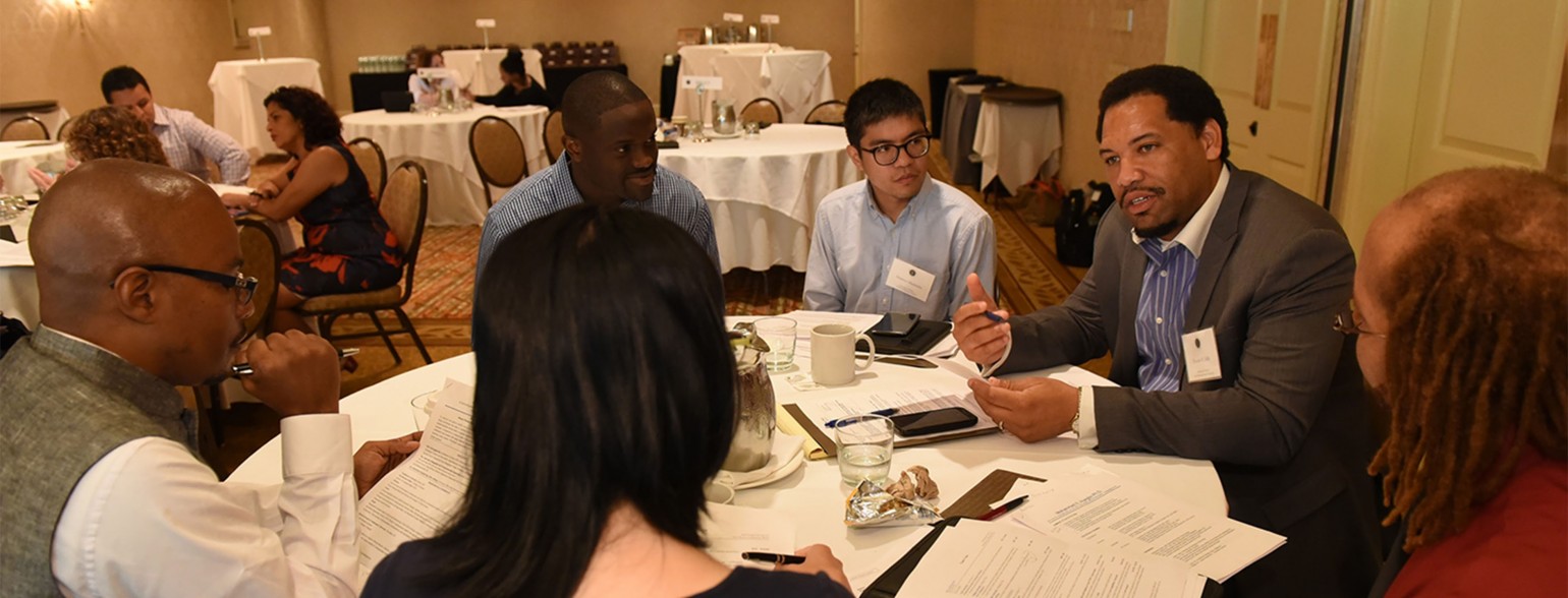 group of people at table listening to someone speak