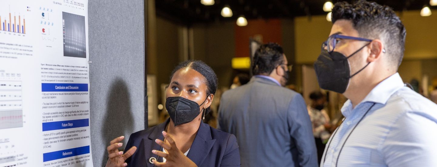 student presenting poster to attendee