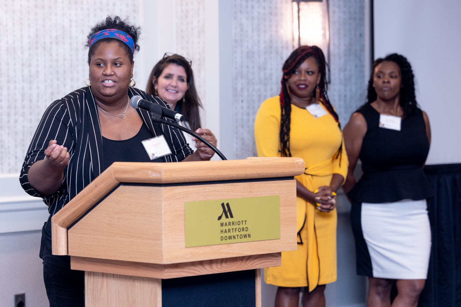 african american women at podium speaking other women behind her
