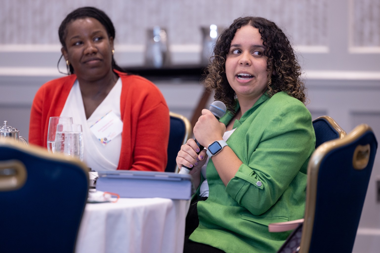 woman sitting at table speaking into a microphone