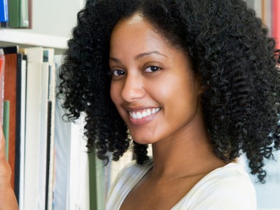 female university student selecting library book from shelf