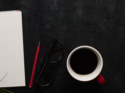 cup of coffee, notebook, pencil and eyeglasses on table