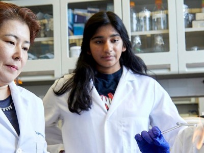 Two young female students and their mentor working in a laboratory