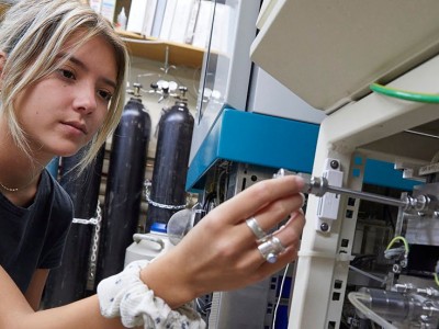 Young female student working at a machine with a screwdriver